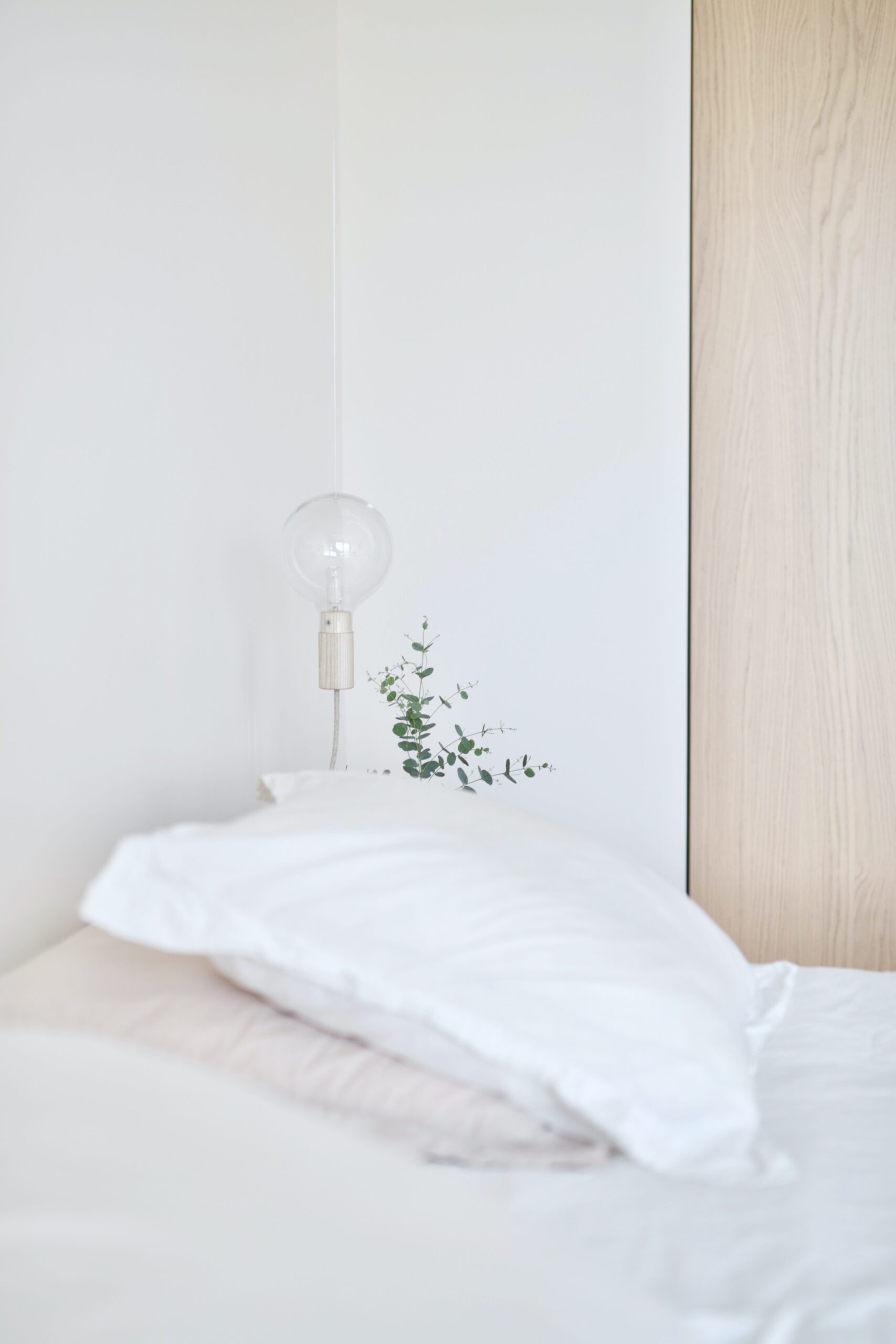 Scandinavian bedroom detail with crisp white linens and light wood accents